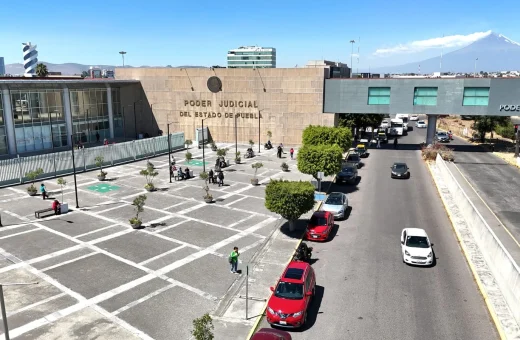 Vista aérea de la fachada del edificio del Poder Judicial del Estado de Puebla, con explanada, vialidad y el volcán Popocatépetl al fondo.